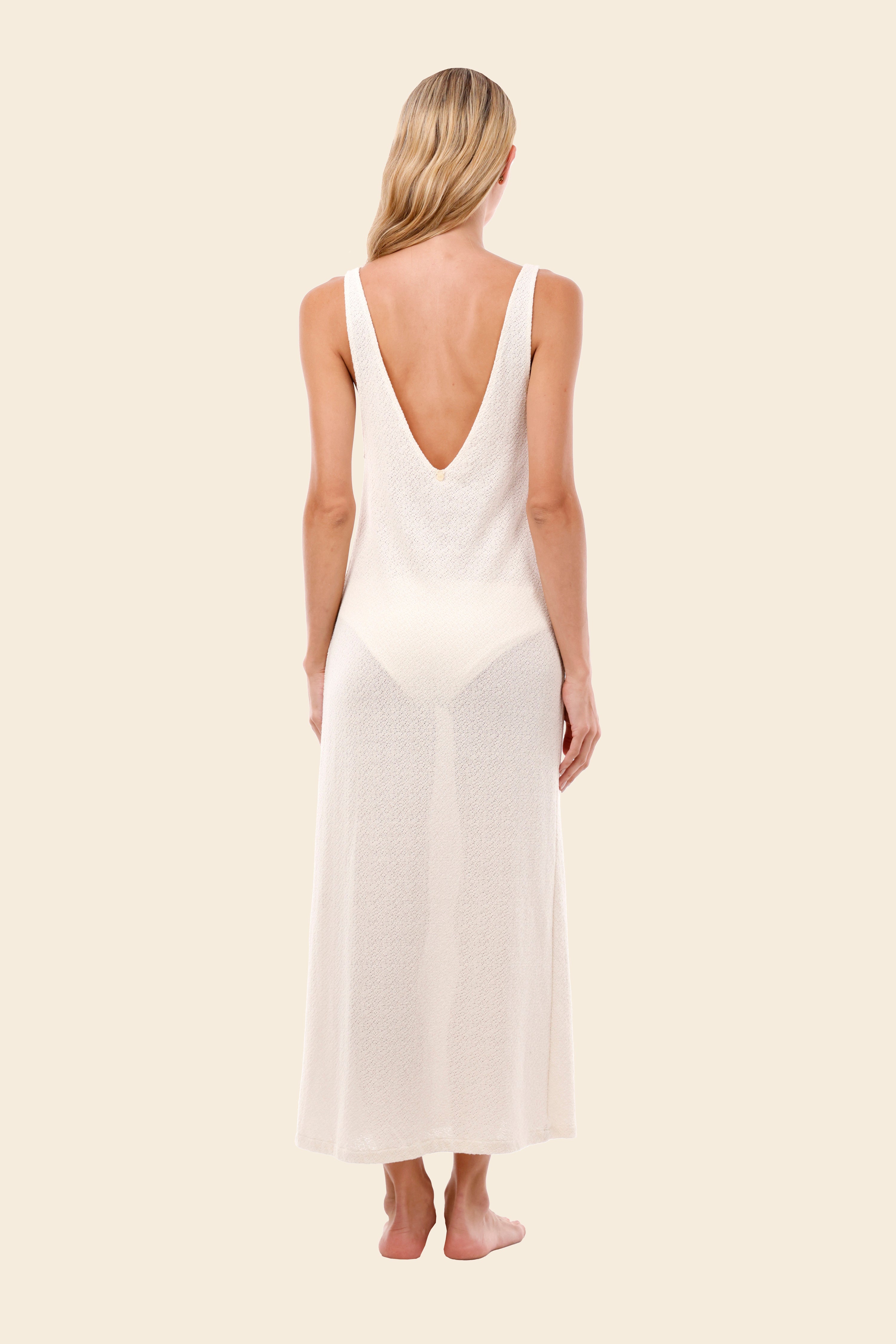 Woman wearing a white dress with a deep backless design on a beige background
