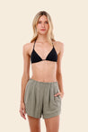 Woman wearing a black bikini top and green shorts